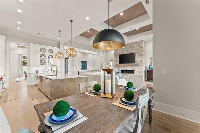 dining area featuring recessed lighting, light wood-style flooring, a brick fireplace, and baseboards