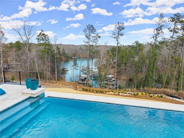 view of swimming pool featuring a fenced in pool, a forest view, and a water view