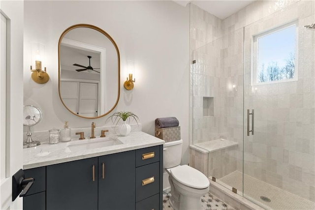 bathroom featuring vanity, a ceiling fan, a shower stall, and toilet