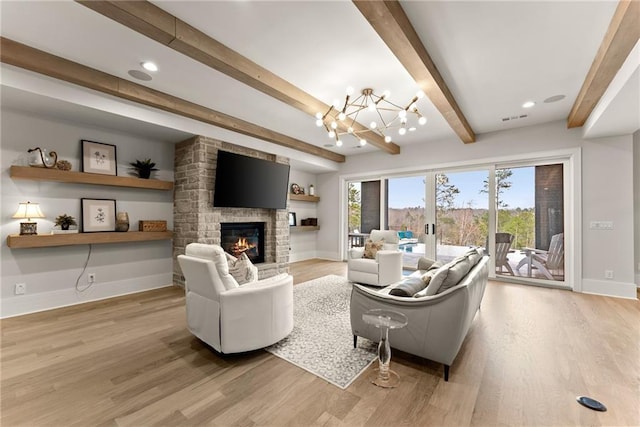 living room with visible vents, baseboards, an inviting chandelier, light wood-style flooring, and a fireplace