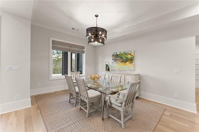 dining room with visible vents, baseboards, light wood finished floors, an inviting chandelier, and crown molding