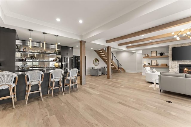 kitchen with hanging light fixtures, open floor plan, light wood-type flooring, and a kitchen bar