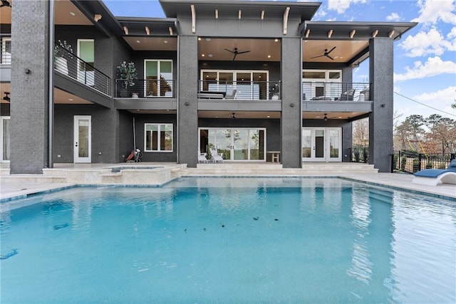 view of swimming pool featuring a patio, fence, a pool with connected hot tub, ceiling fan, and french doors