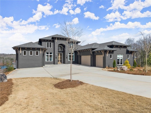 view of front facade featuring brick siding, driveway, a garage, and roof with shingles