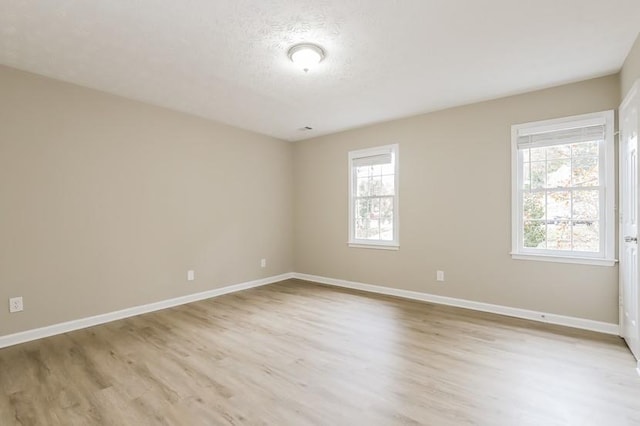 unfurnished room with a textured ceiling and light hardwood / wood-style flooring