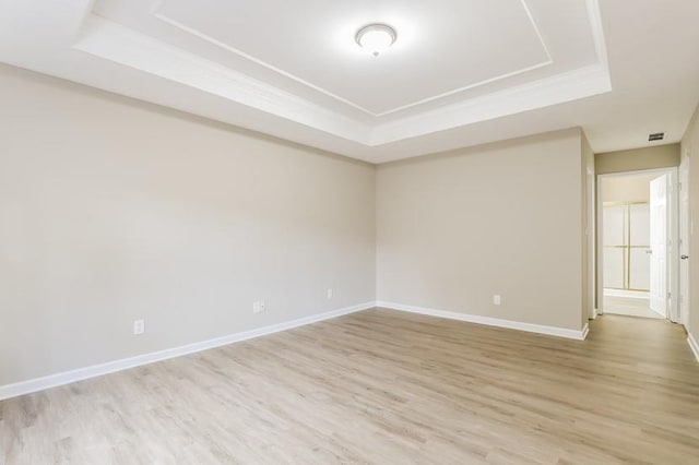 unfurnished room with a raised ceiling, crown molding, and light hardwood / wood-style flooring