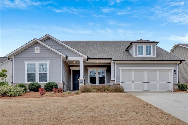 craftsman inspired home featuring a garage and a front lawn