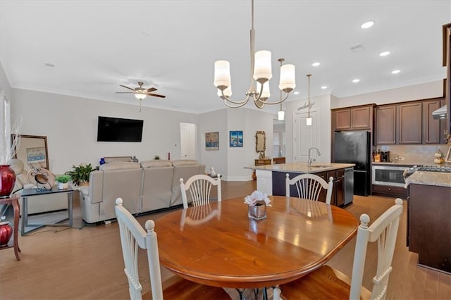 dining area featuring crown molding, sink, ceiling fan with notable chandelier, and light hardwood / wood-style flooring