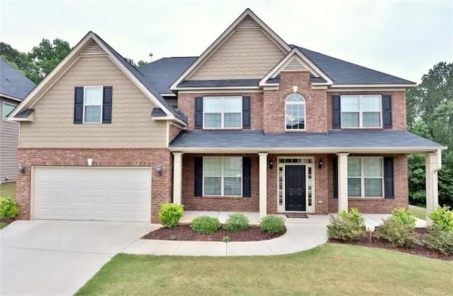 craftsman-style home featuring a garage, a front yard, concrete driveway, and brick siding