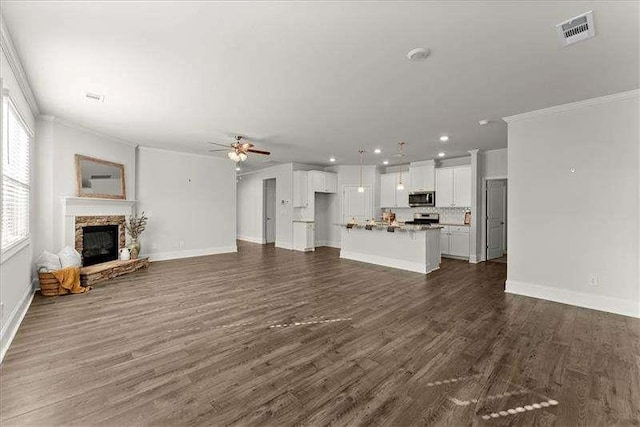 unfurnished living room with ceiling fan, a fireplace, visible vents, and crown molding