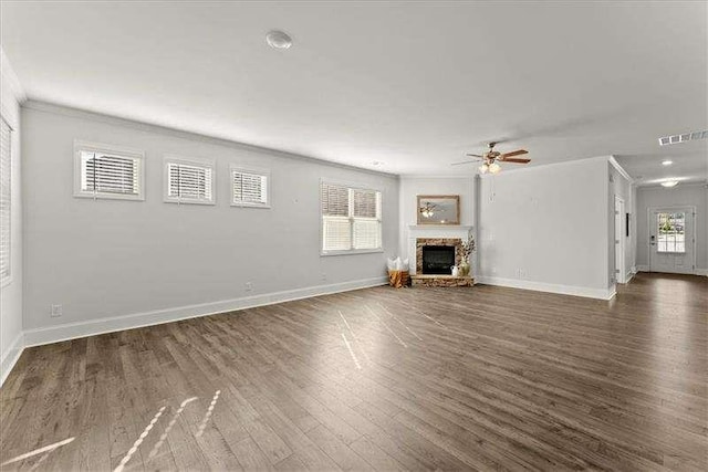 unfurnished living room with visible vents, a fireplace, baseboards, and wood finished floors