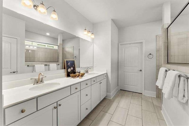 bathroom featuring double vanity, walk in shower, a sink, and baseboards