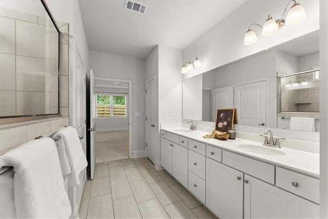 bathroom with double vanity, a sink, visible vents, and a shower with door