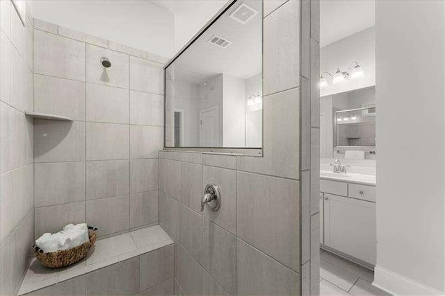 full bathroom with tile patterned flooring, visible vents, tiled shower, and vanity