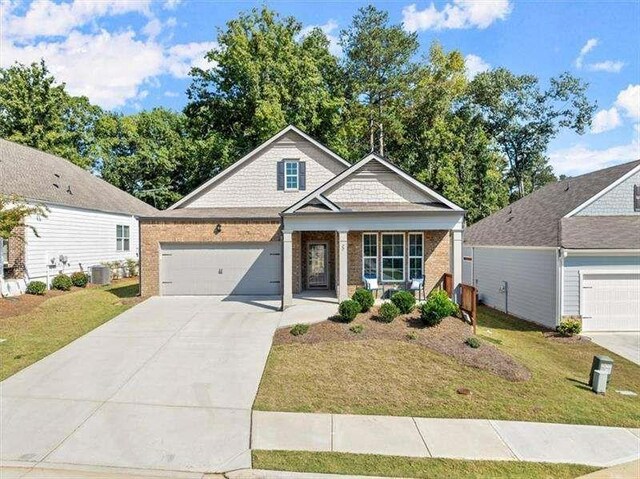 view of front of property featuring a garage, covered porch, and a front lawn