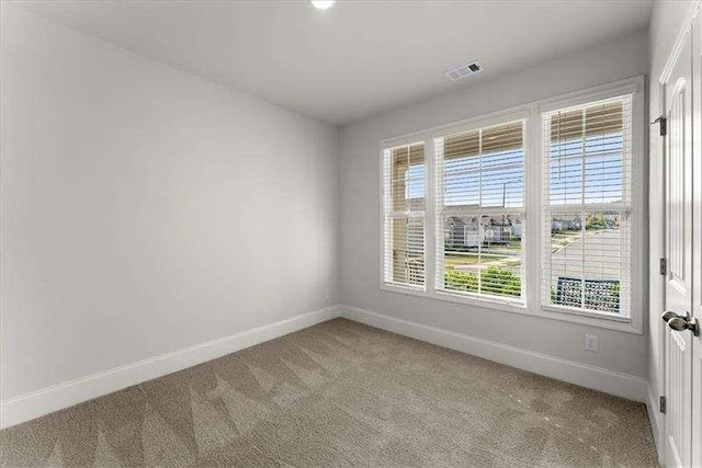 empty room with light carpet, visible vents, and baseboards