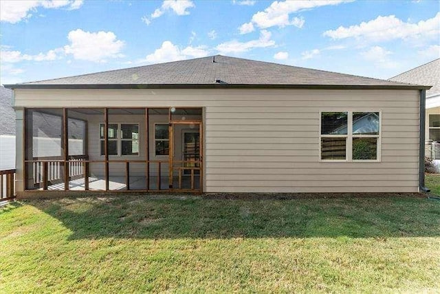 back of property featuring a sunroom, a shingled roof, and a lawn