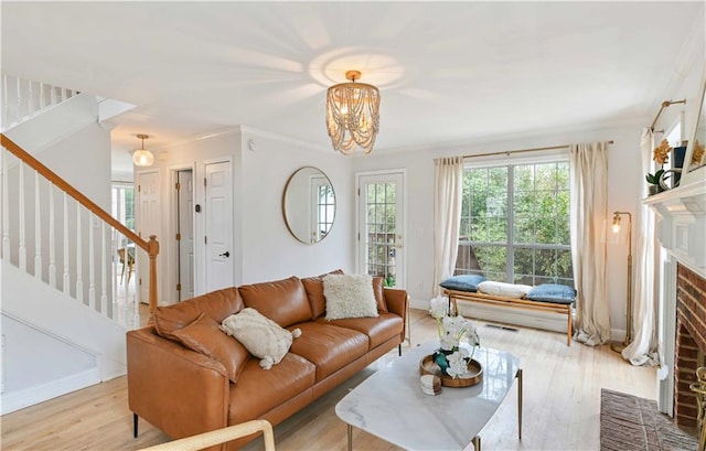 living room featuring stairs, ornamental molding, a fireplace, and wood finished floors