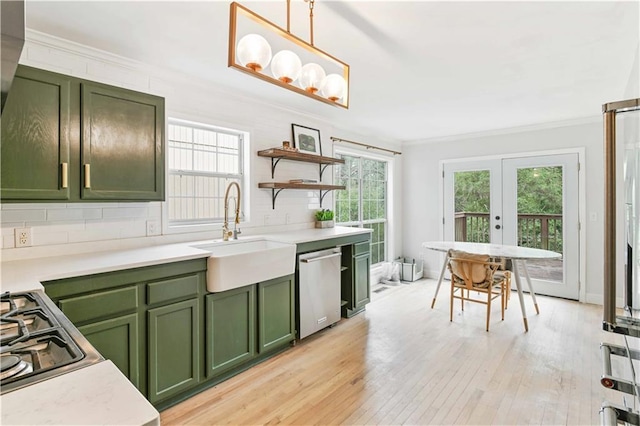 kitchen with appliances with stainless steel finishes, crown molding, a sink, and green cabinets