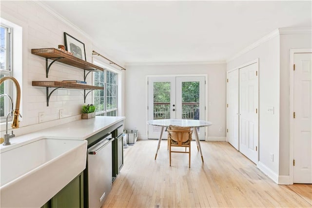 kitchen featuring light wood-style flooring, a sink, stainless steel dishwasher, open shelves, and crown molding