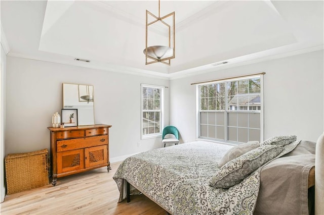 bedroom featuring a raised ceiling, visible vents, and crown molding