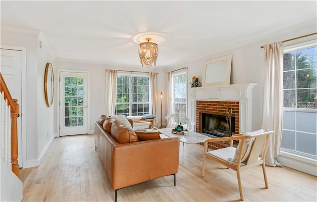 living area featuring baseboards, ornamental molding, stairs, light wood-type flooring, and a fireplace