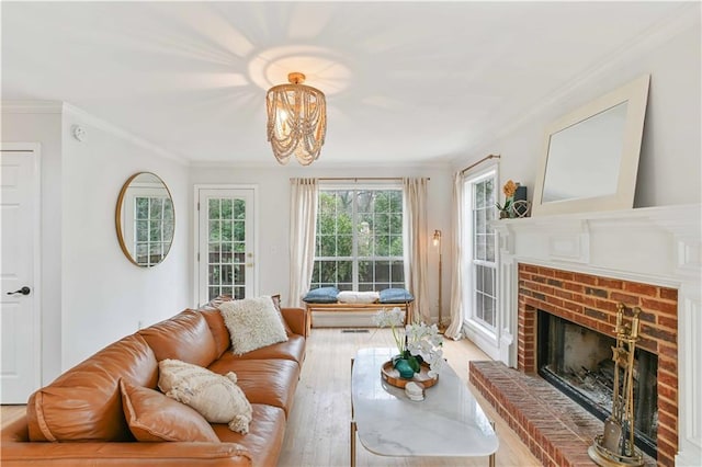 living room featuring ornamental molding, a brick fireplace, and light wood-style flooring