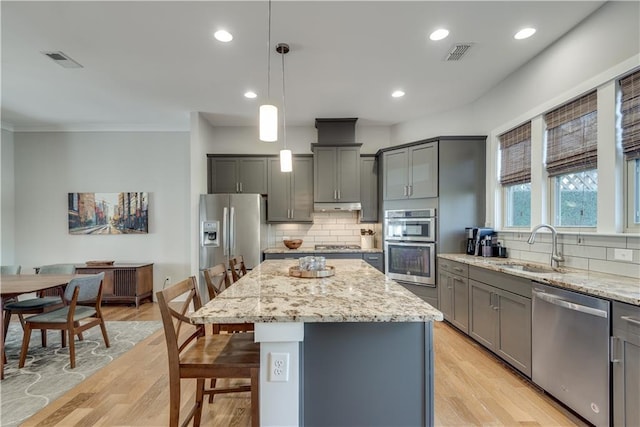 kitchen featuring sink, hanging light fixtures, a kitchen island, stainless steel appliances, and a kitchen bar