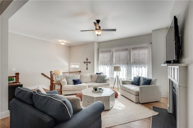 living room featuring hardwood / wood-style flooring, ornamental molding, and ceiling fan