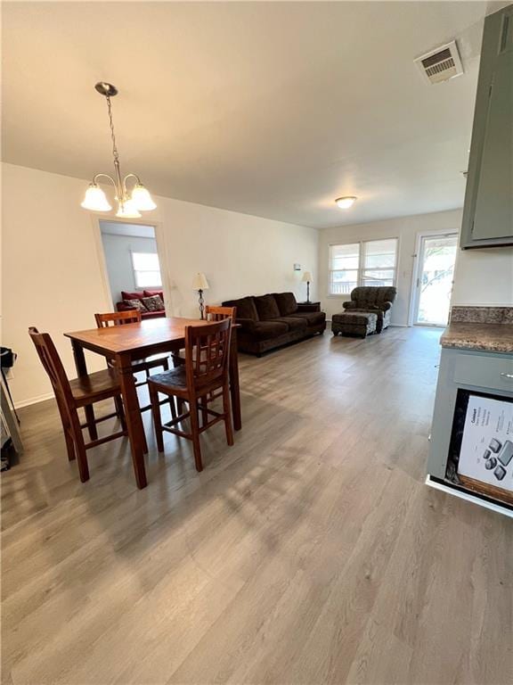 dining space featuring light wood-style flooring, visible vents, and an inviting chandelier
