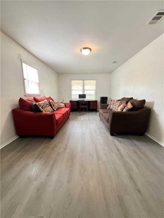 living area with baseboards, visible vents, and light wood finished floors