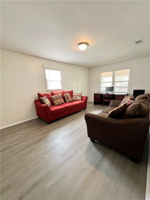 living room with baseboards, visible vents, and wood finished floors