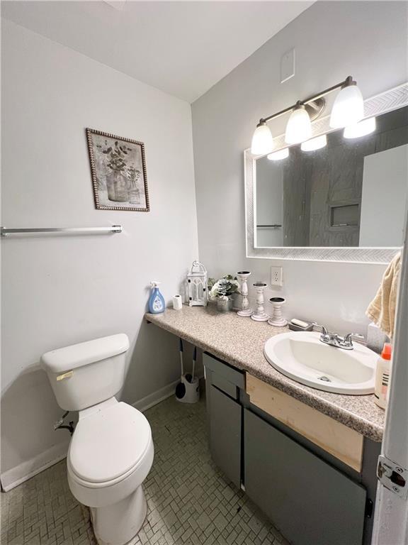 bathroom featuring baseboards, toilet, and vanity
