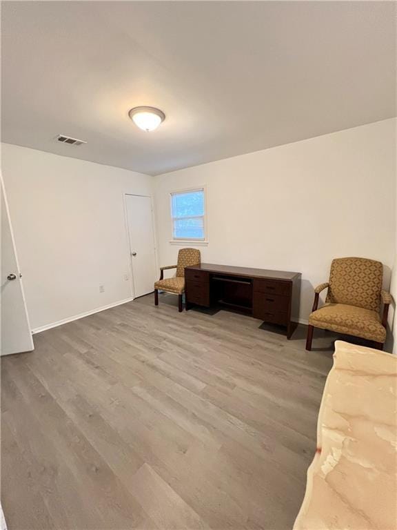 living area with baseboards, visible vents, and wood finished floors