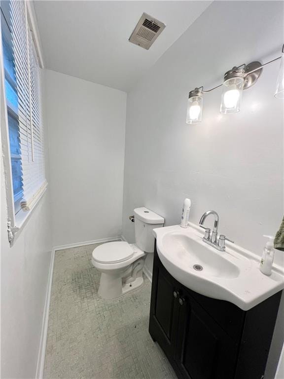 bathroom featuring toilet, vanity, baseboards, and visible vents
