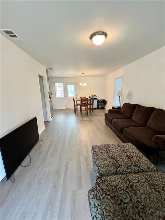 living room featuring a notable chandelier, visible vents, and light wood-type flooring