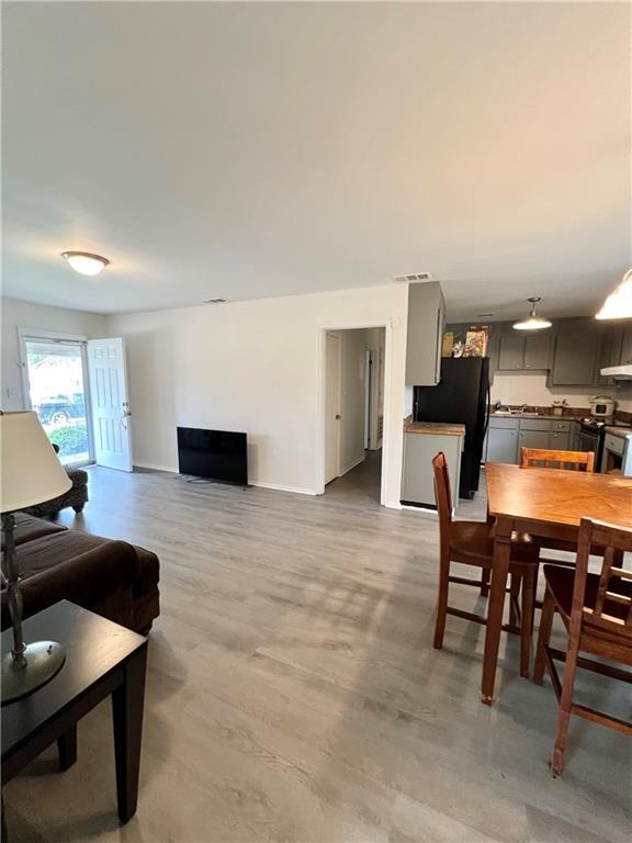 dining space featuring light wood-type flooring, baseboards, and visible vents