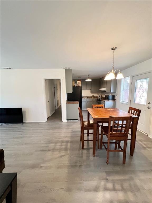 dining room featuring baseboards, visible vents, an inviting chandelier, and wood finished floors