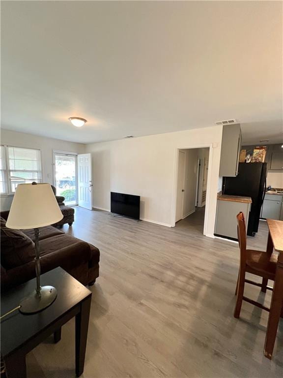 living room with baseboards, visible vents, and wood finished floors