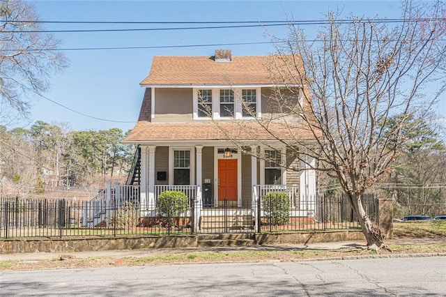 view of front facade with a fenced front yard, covered porch, and a shingled roof