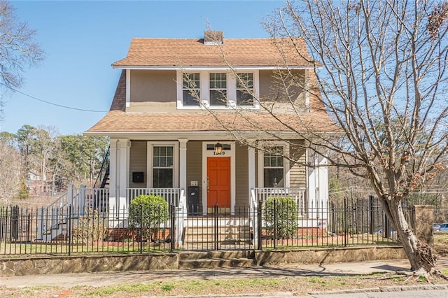 view of front of property with stucco siding, a fenced front yard, a porch, and roof with shingles