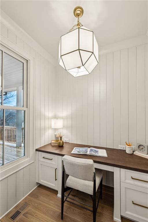 home office with dark wood-type flooring and built in desk