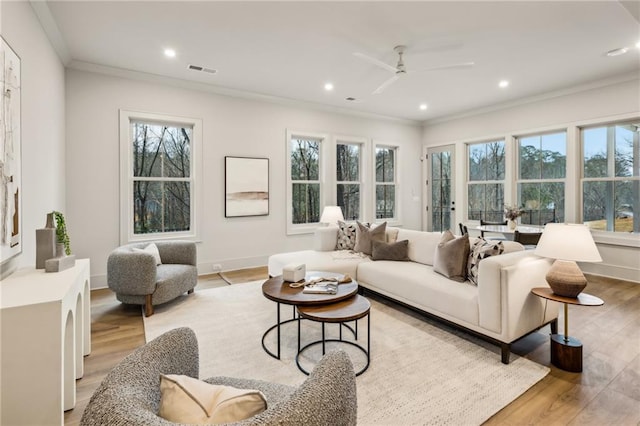 living room with ornamental molding, ceiling fan, and light wood-type flooring