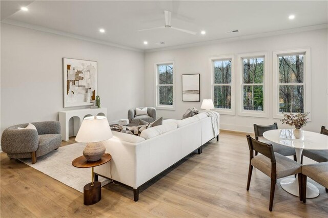 living room with crown molding, ceiling fan, and light hardwood / wood-style flooring