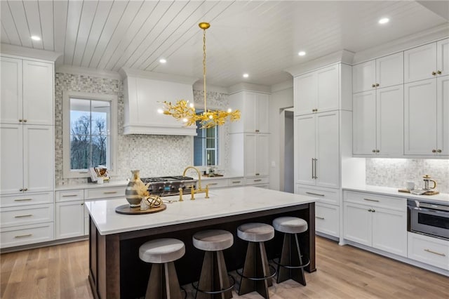 kitchen featuring a kitchen island with sink, pendant lighting, white cabinets, and a breakfast bar