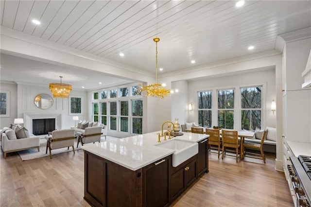 kitchen featuring hanging light fixtures, dark brown cabinets, sink, and light wood-type flooring