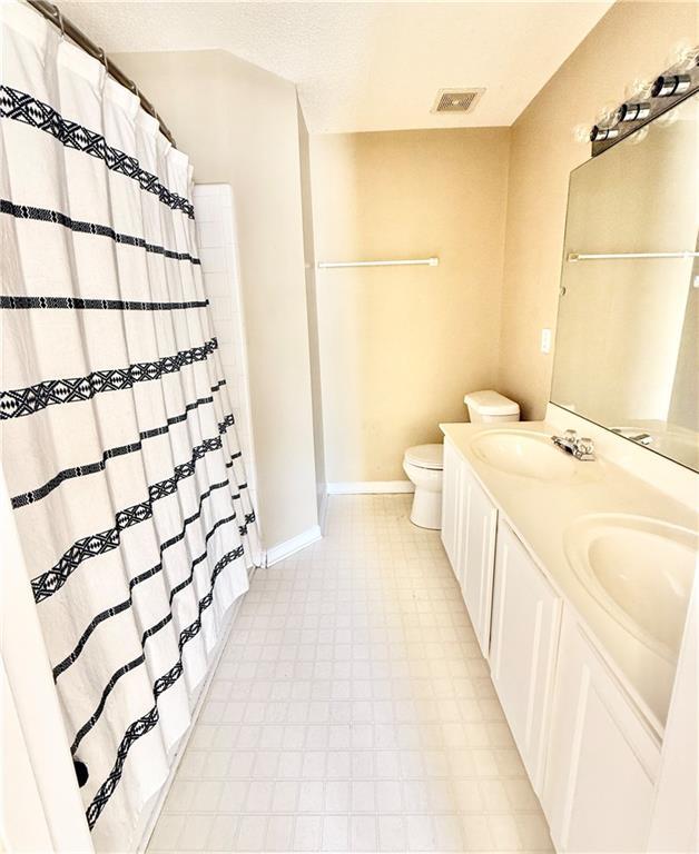 bathroom featuring visible vents, a sink, toilet, and double vanity