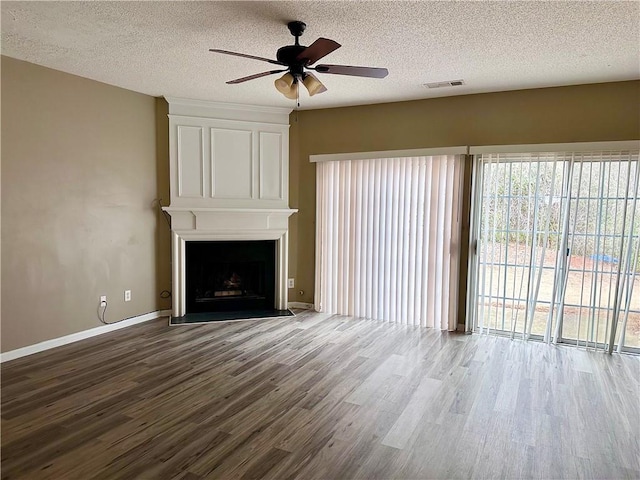 unfurnished living room with visible vents, a ceiling fan, a large fireplace, a textured ceiling, and wood finished floors