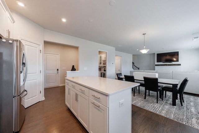 kitchen with dark wood-style floors, stainless steel fridge, white cabinetry, and a center island