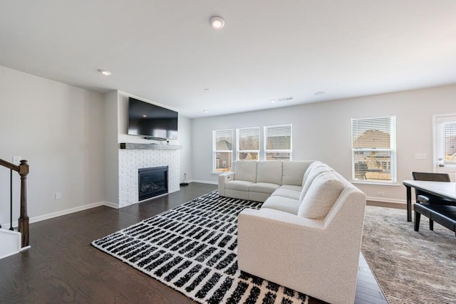 living area featuring dark wood-type flooring, a brick fireplace, recessed lighting, and baseboards